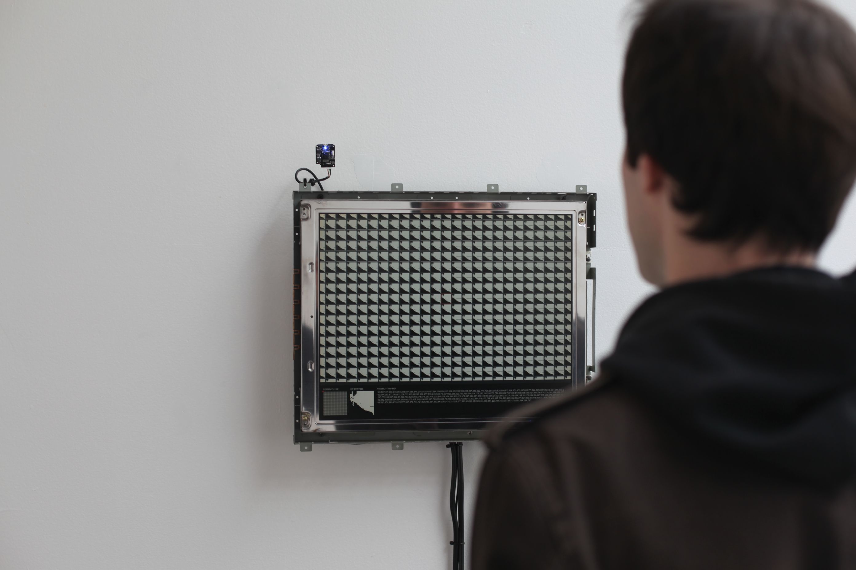 Over-the-shoulder photograph of Joshua Clayton looking at All Thumbs artwork