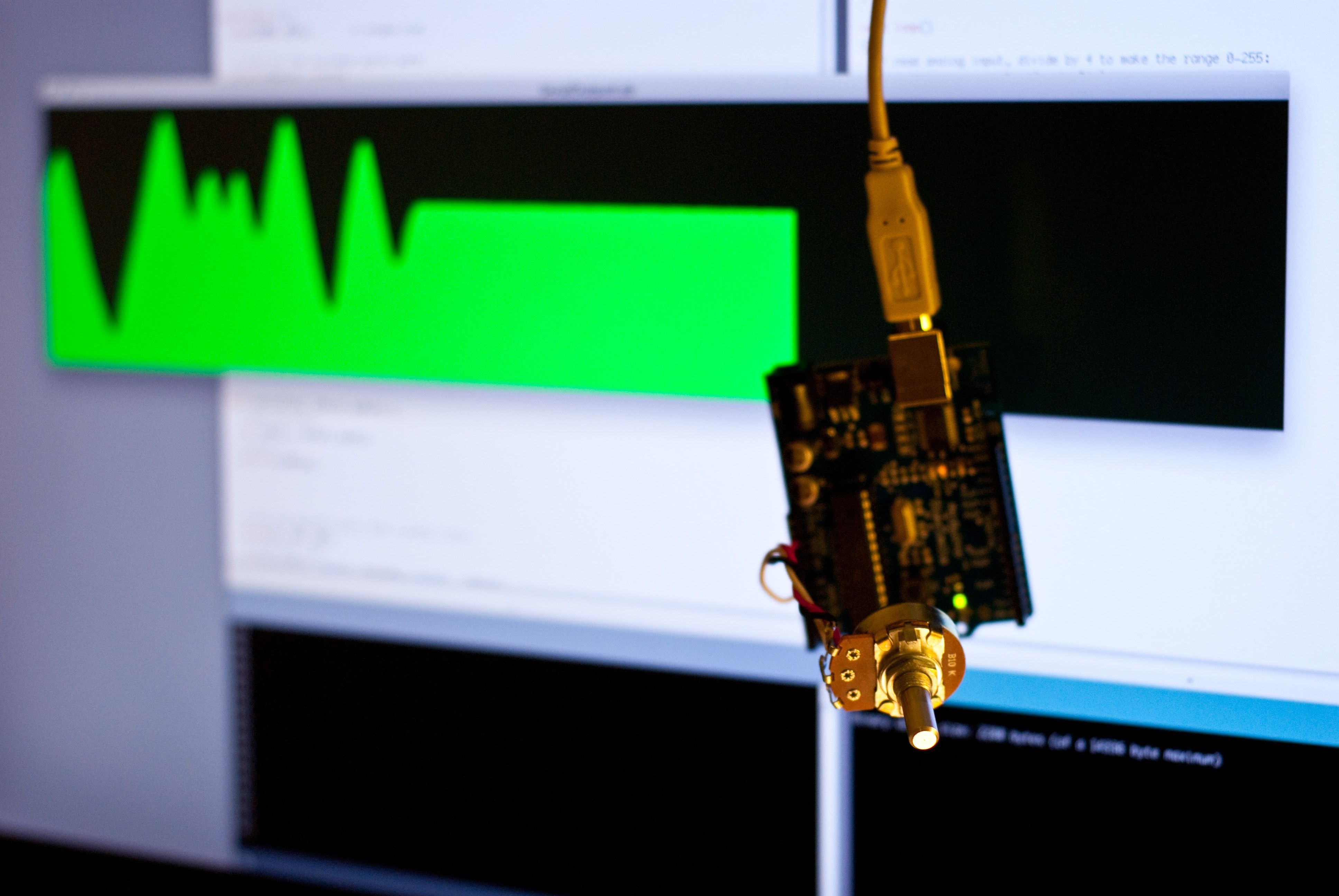 An Arduino with a potentiometer in front of a monitor displaying its output