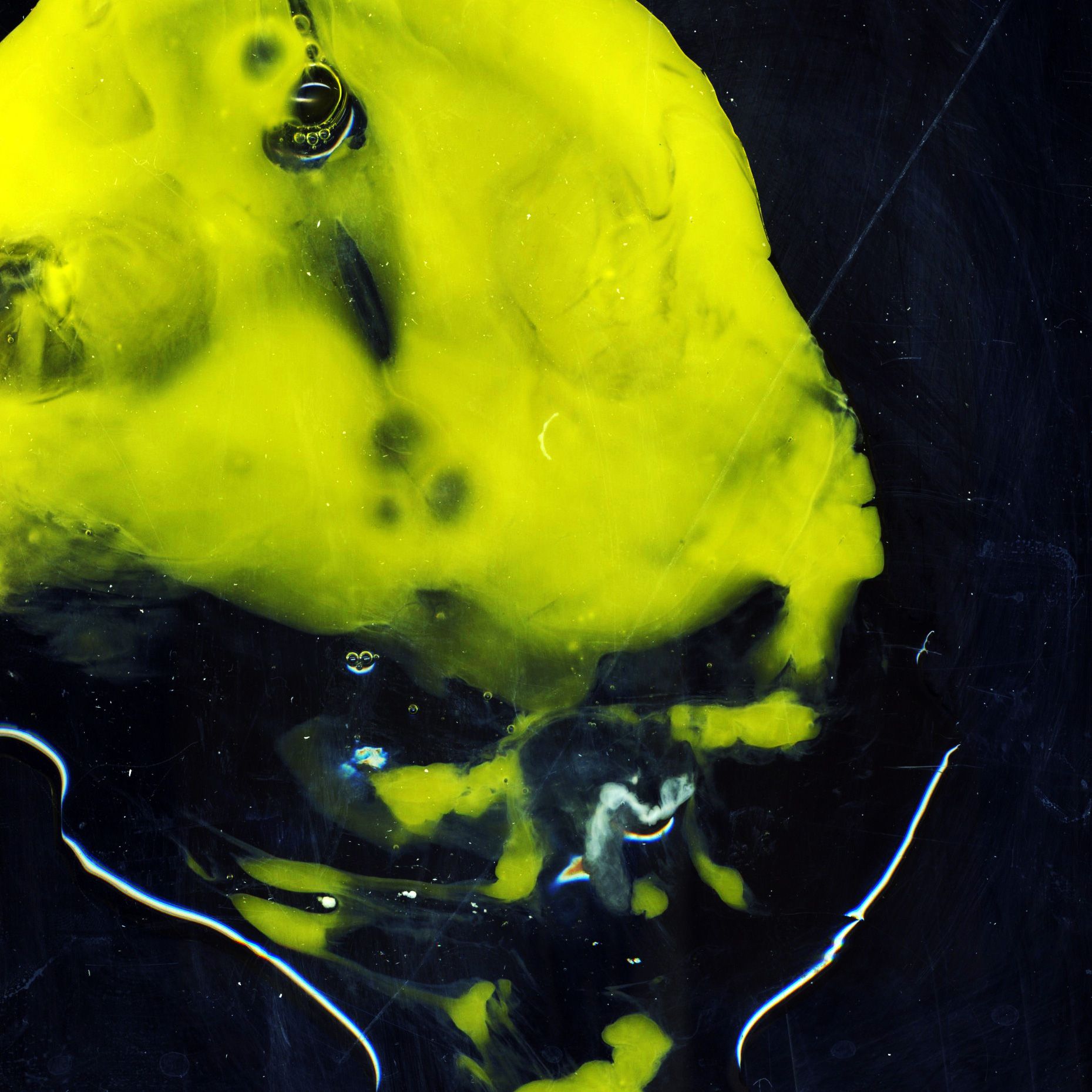 A neon yellow egg yolk splattered across a black background.