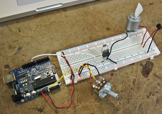 An Arduino connected to a breadboard with a potentiometer, transistor, and motor