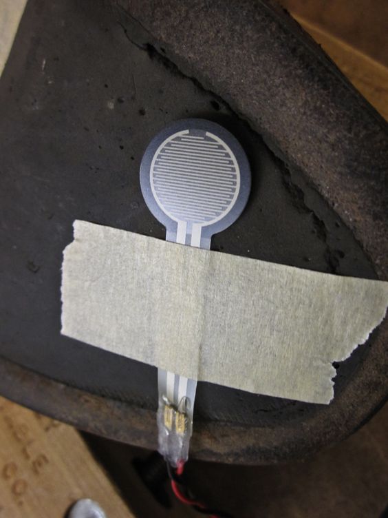 Close up of a sensor taped adjacent a worn area on the sole of a shoe