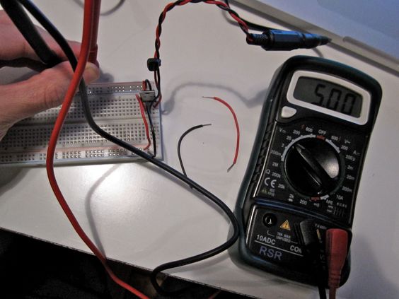 A multimeter checking voltage on a breadboard