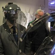 A man wearing an unusual headset suspending a large semi-transparent polarized disk in front of his face.