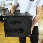 A person holding a large object with an embedded projector and depth camera.